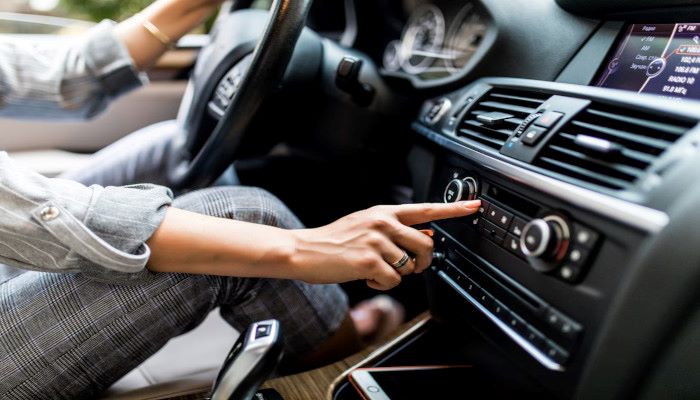 mulher digirindo o seu carro e mexendo no som automotivo